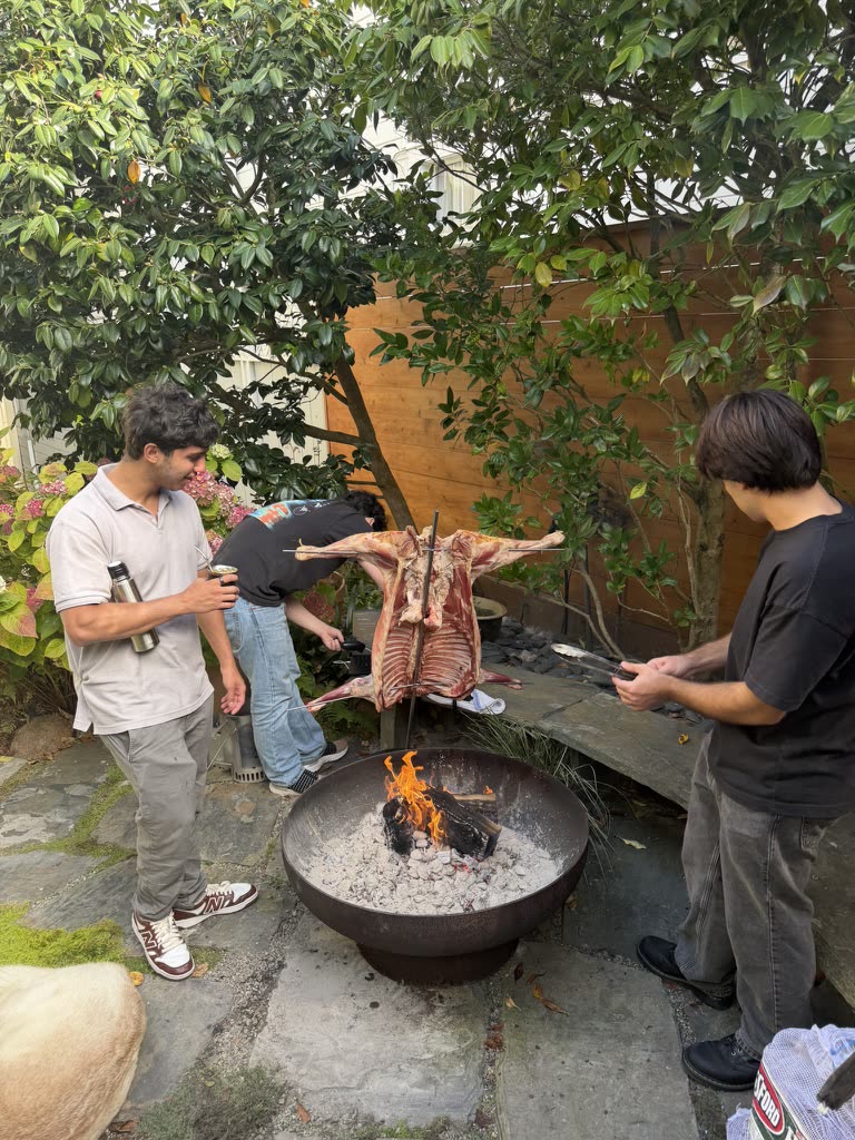 Friends gathered around a wood fire and traditional Argentine asado outdoors